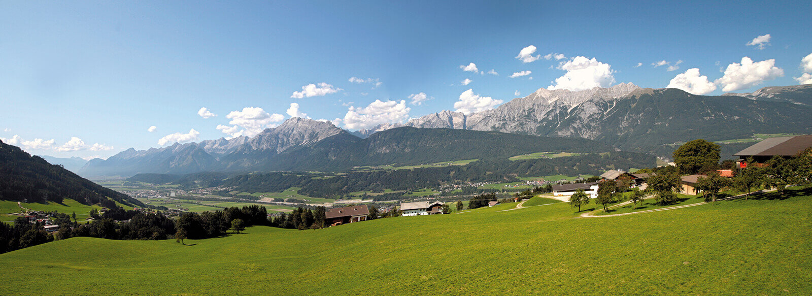 Panoramablick auf bewaldete Berge und ein grünes Tal.