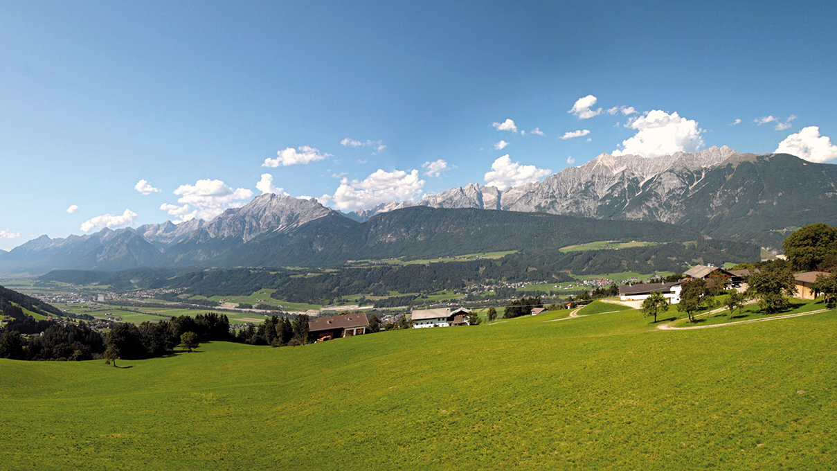 Panoramablick auf bewaldete Berge und ein grünes Tal.
