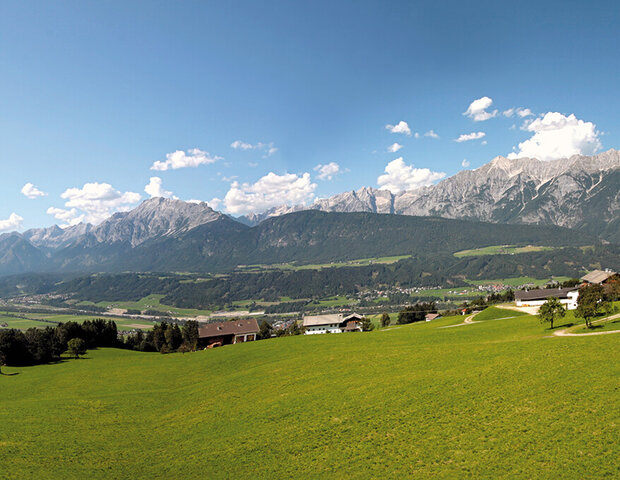 Panoramablick auf bewaldete Berge und ein grünes Tal.
