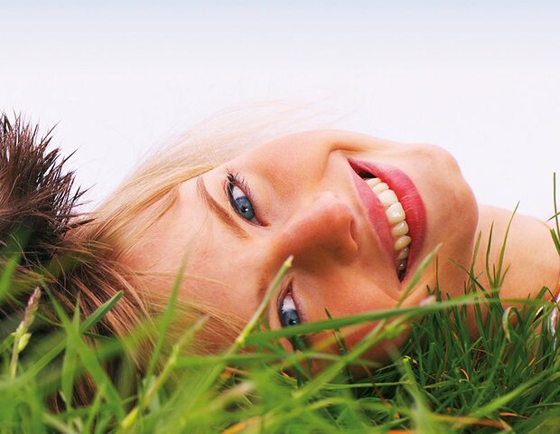 Ein Mann und eine Frau liegen Kopf an Kopf im Gras.