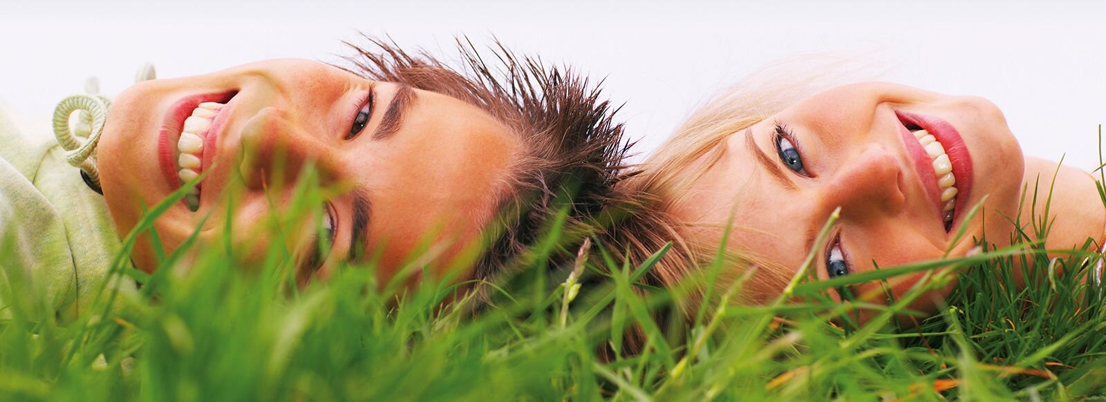 Ein Mann und eine Frau liegen Kopf an Kopf im Gras.