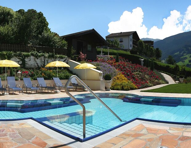 Neben einem Pool stehen Liegen und Sonnenschirme.