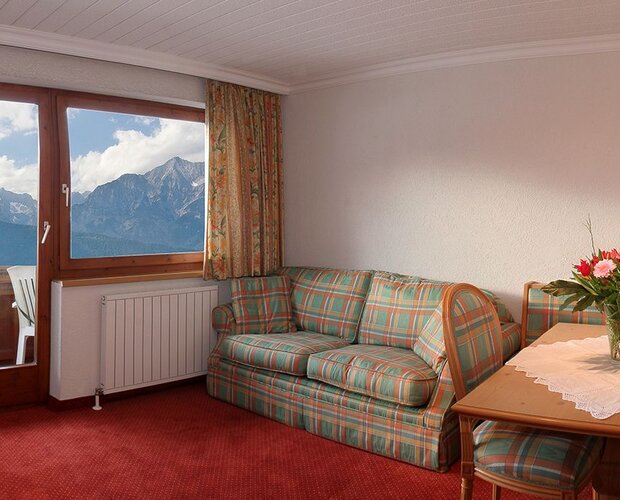 Hotelzimmer mit Sofa, Fernseher und Esstisch.