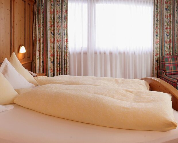 Zimmer mit großem Doppelbett, Schreibtisch und Sessel.