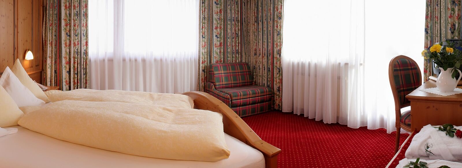 Zimmer mit großem Doppelbett, Schreibtisch und Sessel.