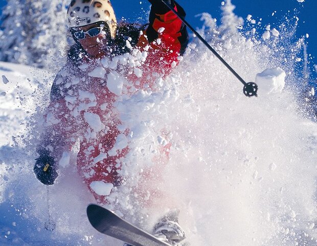 Ein Skifahrer rast eine Piste hinunter.