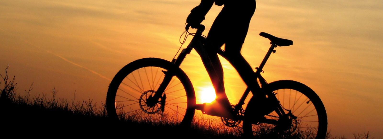 Eine Mountainbiker fährt bei Sonnenaufgang.